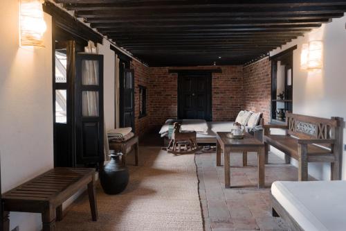 a room with benches and a bed and a brick wall at Peacock Guest House in Bhaktapur