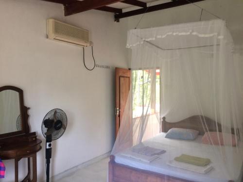 a bedroom with a bed with a window and a fan at Hansa Villa in Unawatuna
