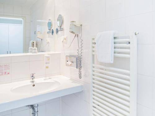 a white bathroom with a sink and a mirror at Hotel Domicil Hamburg by Golden Tulip in Hamburg