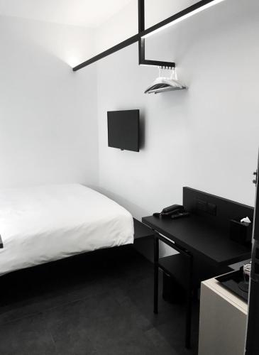 a white bedroom with a bed and a desk at Hotel Mono in Singapore