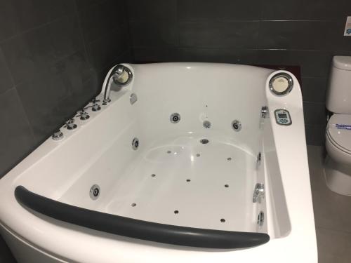 a white bath tub in a bathroom with a toilet at Deluxe Hostels & Suites Merida in Merida