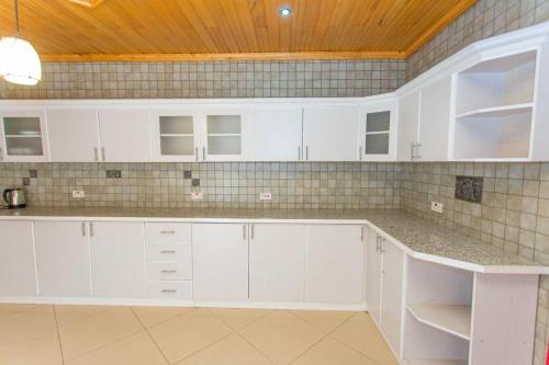 a kitchen with white cabinets and a wooden ceiling at Iris Guest House in Kigali