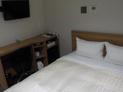 een slaapkamer met een bed en een tv aan de muur bij Hotel Crown Hills Katsuta Nigo Motomachiten in Hitachinaka
