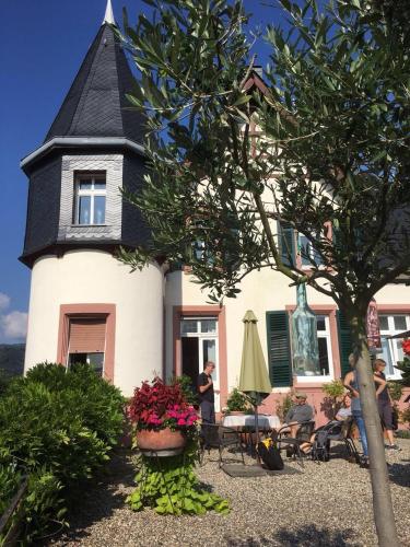 a white house with a black roof with flowers in front at Wohnen im Burghotel in Lorch am Rhein