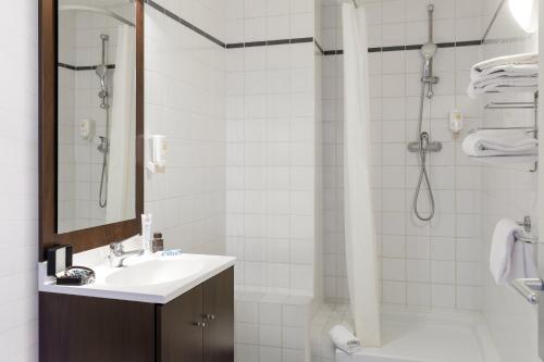 La salle de bains est pourvue d'un lavabo et d'une douche. dans l'établissement Aparthotel Adagio Access Lille Vauban, à Lille