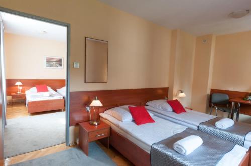 スカルジスコ・カミエンナにあるHotel Komesのベッドルーム1室(赤い枕のベッド2台付)