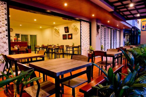 a restaurant with wooden tables and chairs and plants at Krabi Cinta House in Krabi town