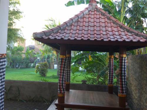 a gazebo with a tiled roof in a yard at Master Homestay in Amed