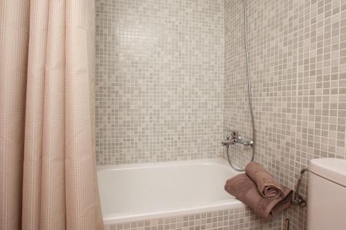 a bathroom with a white tub and a shower curtain at Apartment Beach Front Canet in Canet de Mar