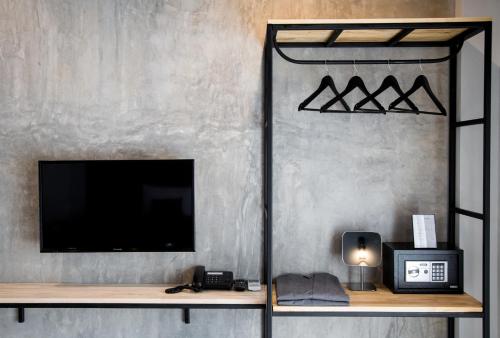 a living room with a tv and a shelf with a television at The Rodman Hotel in Chiang Mai