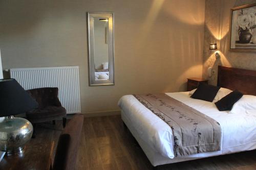 a bedroom with a bed and a chair and a mirror at Hôtel Restaurant Le Moulin de Saint Verand in Saint-Vérand