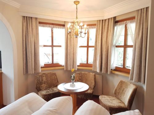 a living room with a table and chairs and windows at Hotel Ehrenreich in Sankt Anton am Arlberg