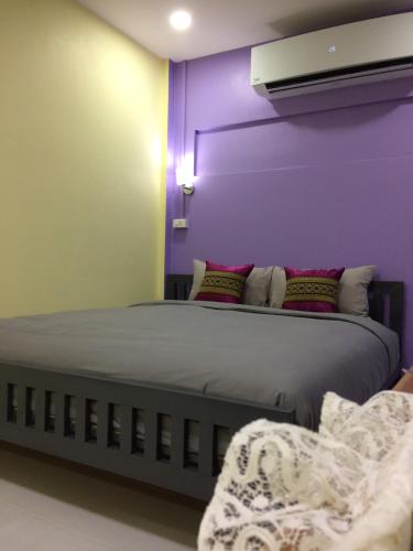 a bedroom with a large bed with purple walls at Smilingface guesthouse in Sukhothai