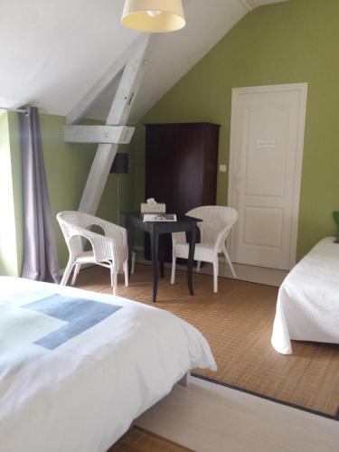 une chambre avec un lit, un bureau et des chaises dans l'établissement chambres des rosiers, à Sennevières