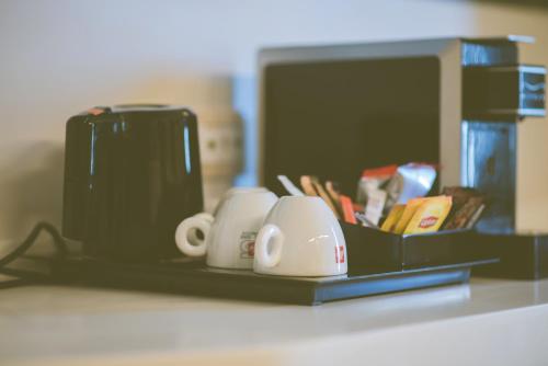 a counter top with a coffee maker and coffee cups at Kastro Hotel in Heraklio Town