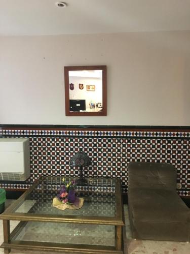 a living room with a glass table and a chair at Hostal Carlos III in El Ejido