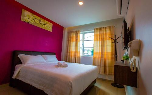 U Plus Budget Hotel في بوكيت ميرتاجام: غرفة نوم بسرير ابيض بجدار وردي