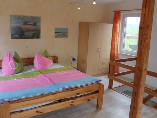 Schlafzimmer mit einem Bett mit rosa und grünen Kissen in der Unterkunft Modern Holiday Home with Garden near Sea in Kagsdorf in Kägsdorf