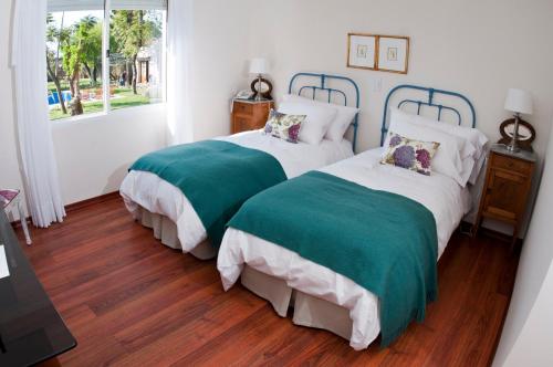 Duas camas com capas verdes e brancas num quarto em Hotel Papiros em Paysandú