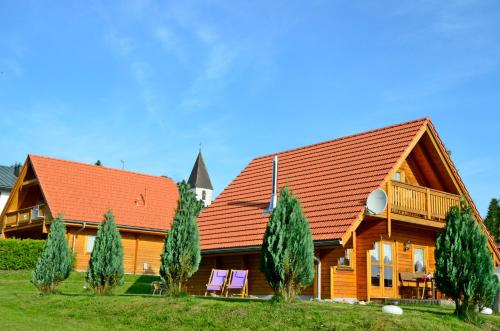 a wooden house with an orange roof and some trees at "Das Jagdhaus"- Hüttenurlaub in Bayern in Philippsreut