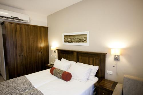 a hotel room with a bed with white sheets and pillows at City Center Jerusalem in Jerusalem