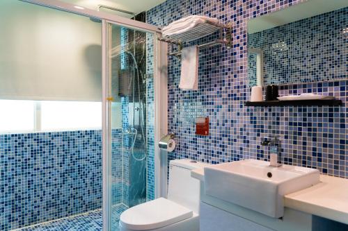 a blue tiled bathroom with a sink and a shower at E-House Hotel in Taipei