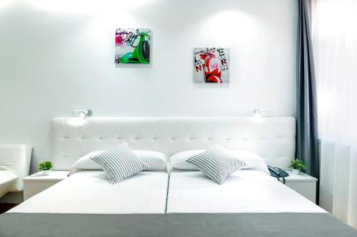 uma cama branca com duas fotografias na parede em Boutique Urban Madrid Serrano em Madri