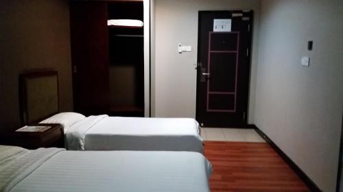 a hotel room with two beds and a door at Hotel Sadong88 in Kota Kinabalu