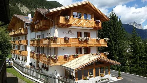 a large building with wooden balconies on a mountain at Hotel Garni Lastei in Pozza di Fassa