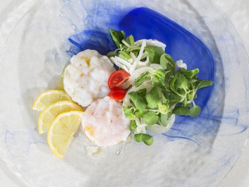 a blue plate of food with shrimp and greens at Mercure Genova San Biagio in Genova
