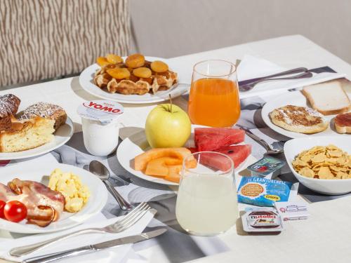 a table topped with plates of breakfast foods and orange juice at Mercure Genova San Biagio in Genova