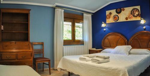Casa Rural Ibarrondo Etxea في موغاينا: غرفة نوم زرقاء مع سرير عليه مناشف