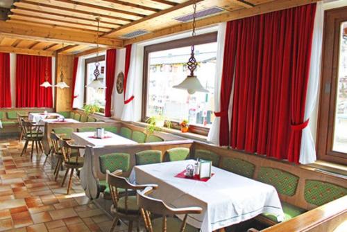 オーバータウエルンにあるHotel Bellaのテーブルと椅子、赤いカーテンが備わるレストラン