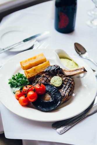 a plate of food with fish and vegetables on a table at voco Letchworth Hall by IHG in Letchworth
