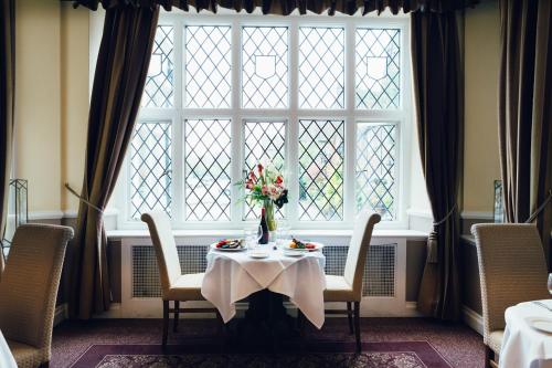 a table with a vase of flowers in front of a window at voco Letchworth Hall by IHG in Letchworth