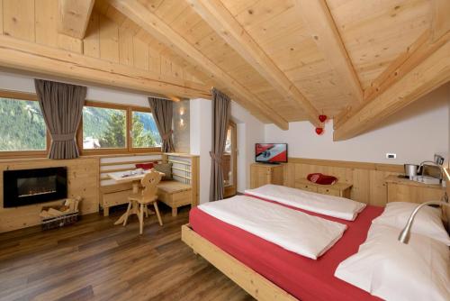 a bedroom with a large bed and a desk at Hotel Garni Lastei in Pozza di Fassa