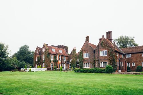 a large brick house with a large green yard at voco Letchworth Hall by IHG in Letchworth