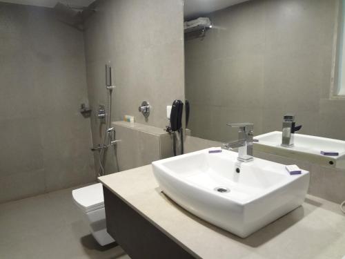 a bathroom with a white sink and a toilet at Veronica Hotel in Vadodara