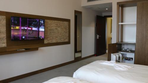a bedroom with a bed and a tv on a wall at Hotel Admiral in Prizren