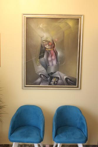 two blue chairs in front of a painting on a wall at Hotel Admiral in Prizren