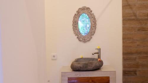 a bathroom with a stone sink and a mirror at Boge House in Ubud