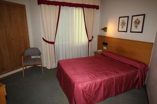 a bedroom with a red bed and a chair at Hotel Ramos in Silleda