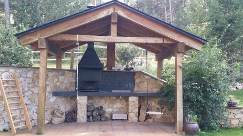 a wooden pavilion with a grill on a stone wall at Cal Manju in La Coma i la Pedra