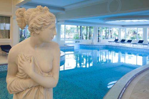 a statue of a woman standing in front of a swimming pool at Grand Hotel Trieste & Victoria in Abano Terme