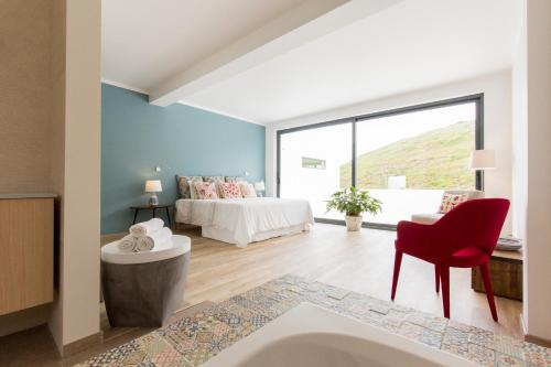 a bedroom with a bed and a red chair at Luxury Beach Villa in Ericeira