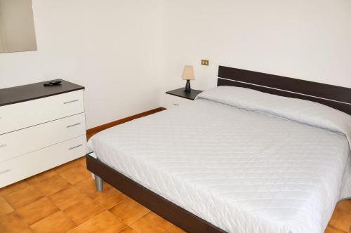 a bedroom with a white bed and a dresser at GiaLoSa Biker House in Villa Verucchio