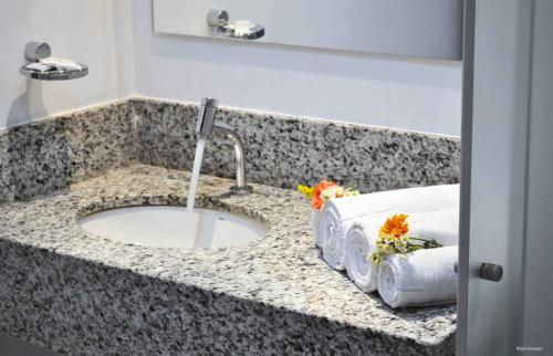 a bathroom counter with a sink with flowers on it at Antonius Imperial Hotel in Santo Antônio de Jesus