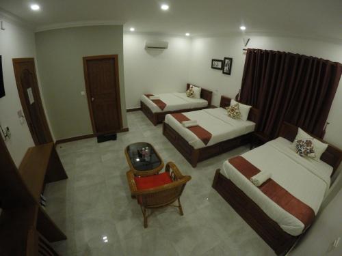 a hotel room with two beds and a chair at Happy​​ Family Guesthouse in Kampot
