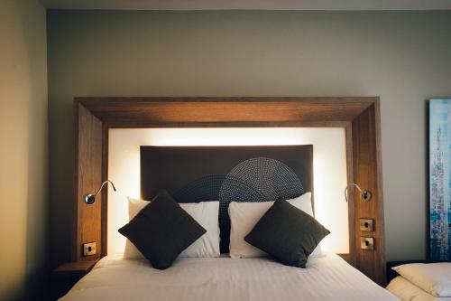 a bedroom with a large bed with a wooden headboard at Novotel Nottingham Derby in Long Eaton