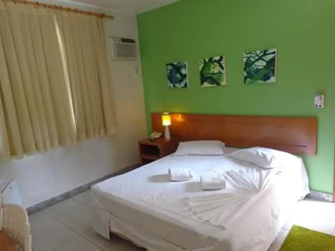 Chonim de BaixoにあるHotel Pinheirosの緑の壁のベッドルーム1室(白いベッド1台付)